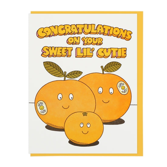 The front of this card depicts two large oranges with happy faces, smiling down on a smaller orange. The large orange on the left has a sticker which reads 