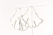Load image into Gallery viewer, A pair of silver earrings made with bent wire to resemble the silhouette of a gingko leaf.
