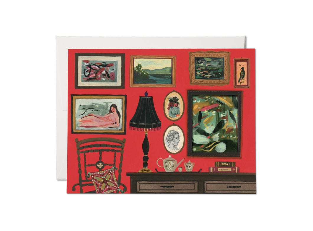 The front of this card depicts a gallery wall filled with beautiful paintings, ranging from abstract to portrait art. There is a rocking chair with a pillow in the lower left corner; and a console table filled with a tea set, a lamp, and books. The largest frame is actually a cut out that leads to the inside of the card.
